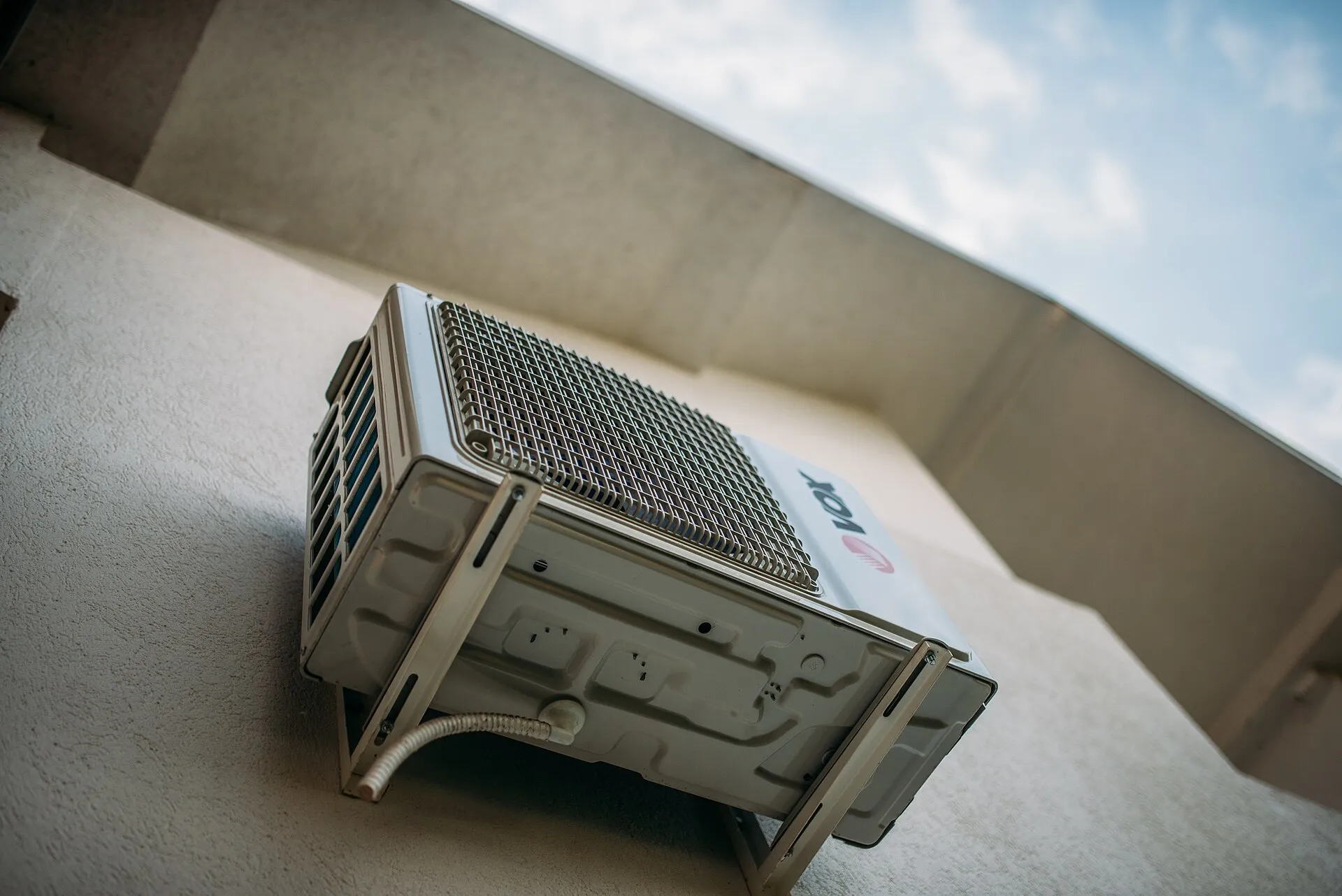 A residential outdoor air conditioning condenser unit against a clear blue sky