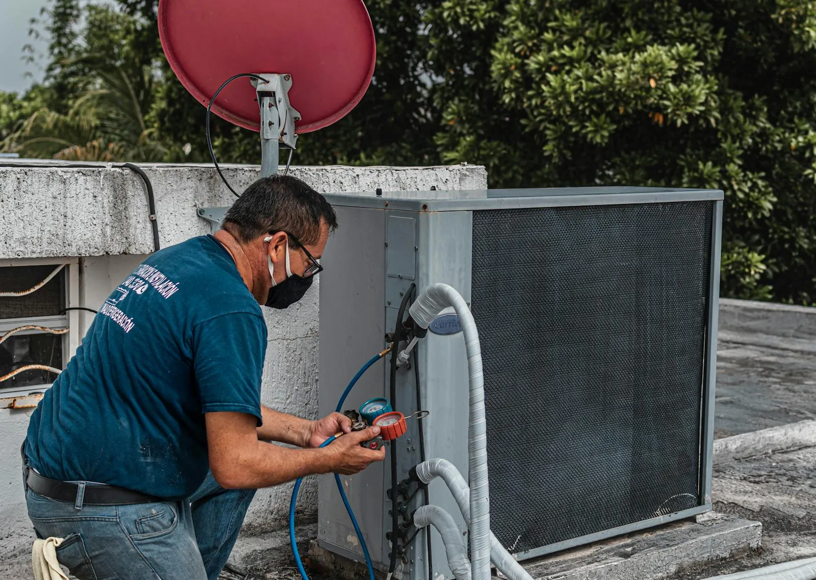 An HVAC technician checking an outdoor air conditioning unit with gauges, diagnosing a compressor